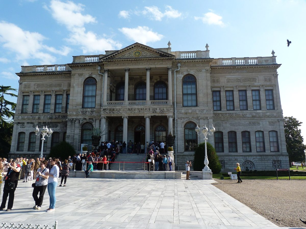 The neoclassical stone front of Dolmabahce Palace with visitors on the forecourt