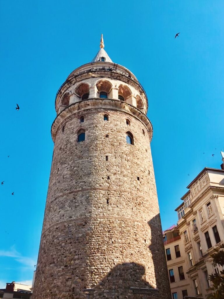 The stone Galata Tower rising above the rooftops of Beyoglu in Istanbul against a blue sky