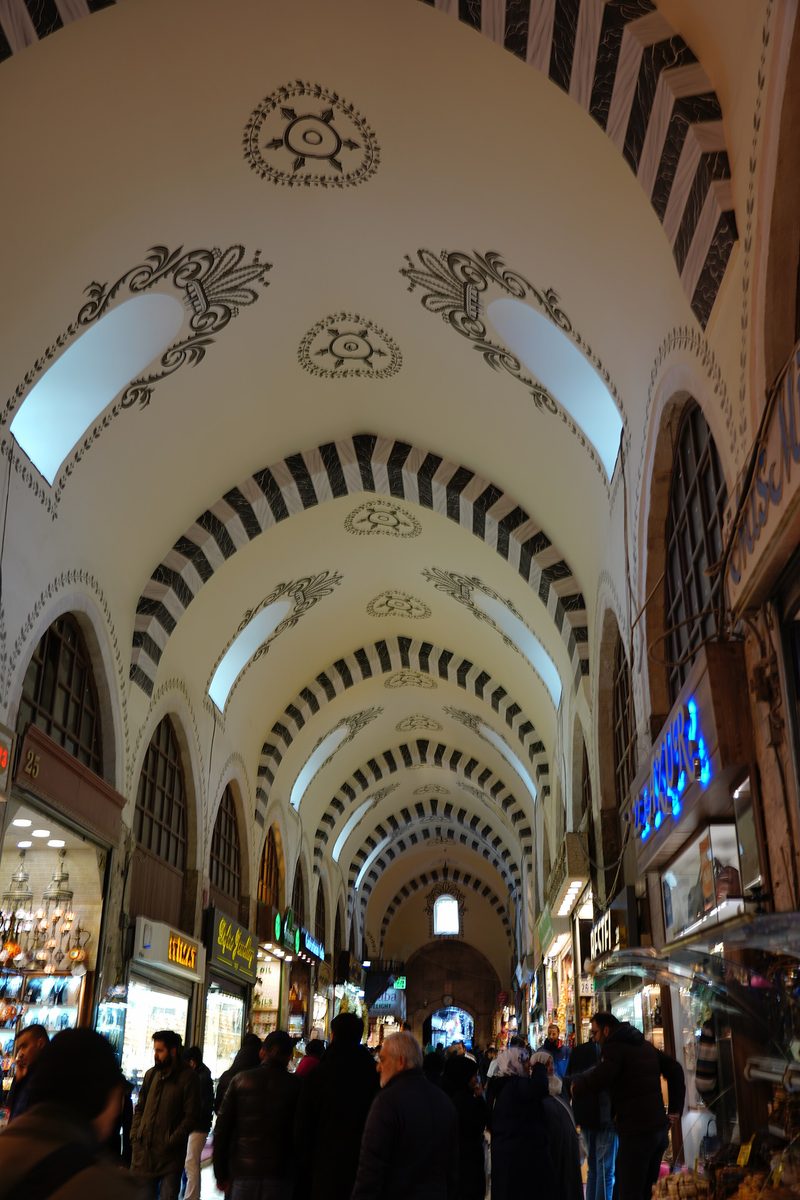 The vaulted interior of the Spice Bazaar in Istanbul with shoppers and striped arches