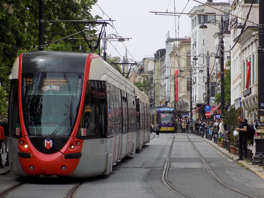 A red T1 tram on a street in Istanbul with pedestrians alongside