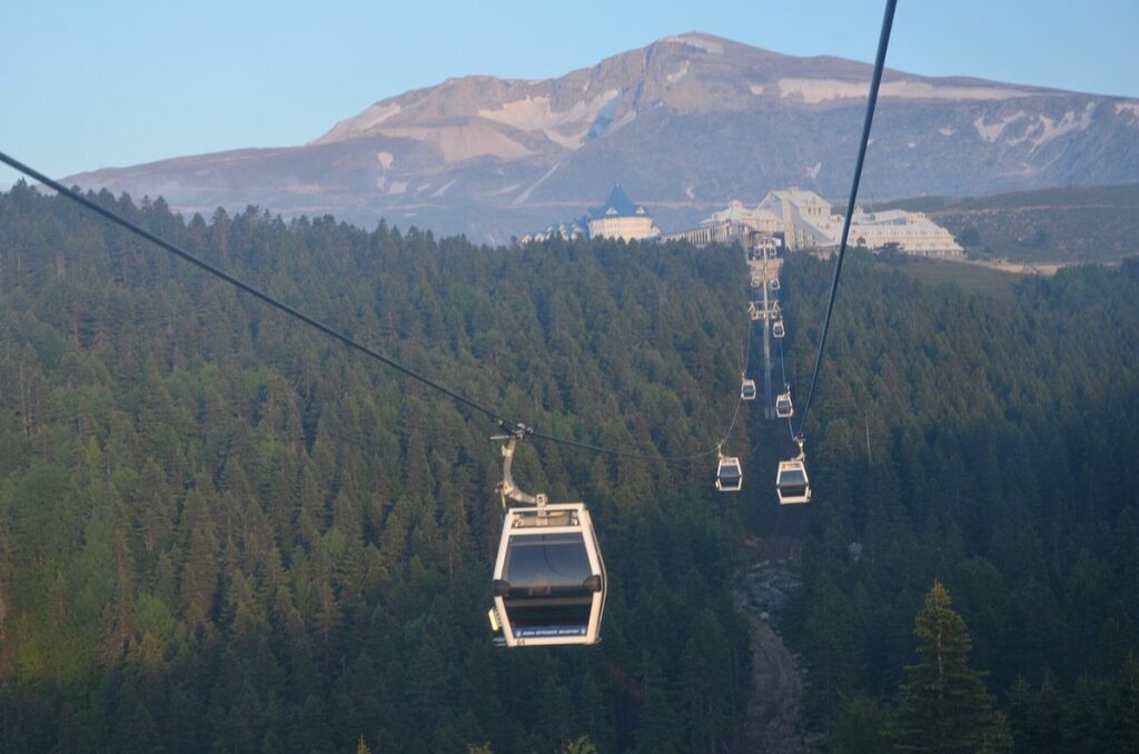Cable car cabins rising over pine forest towards the summit of Uludag above Bursa