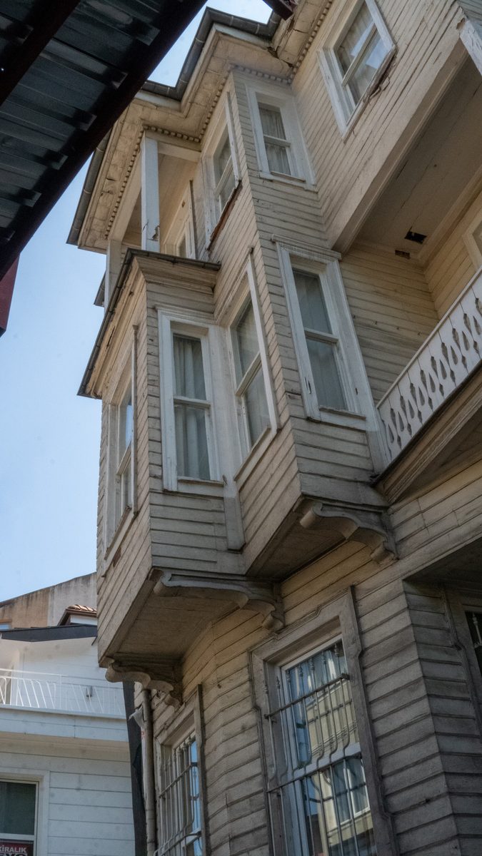 A tall old timber house with stacked bay windows on a street in Arnavutkoy