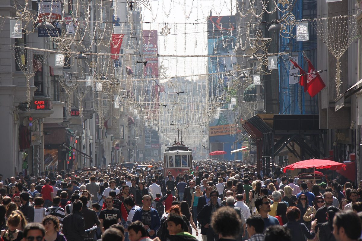 Istiklal Avenue packed with pedestrians from wall to wall, with the red nostalgic tram in the middle distance