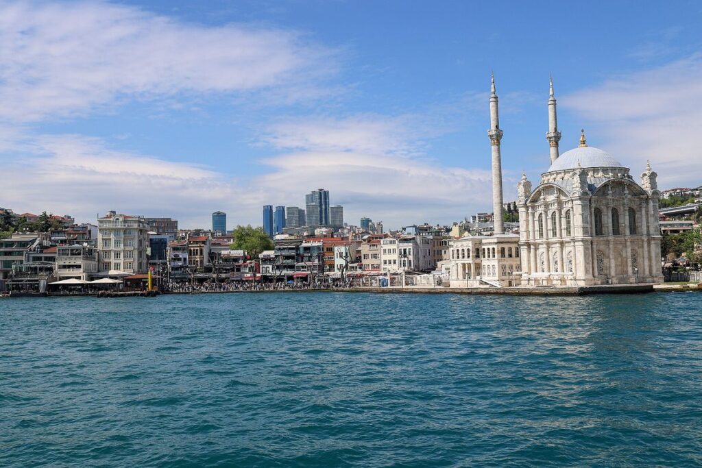 Ortakoy Mosque and its waterfront square seen from the Bosphorus, with apartment blocks rising behind