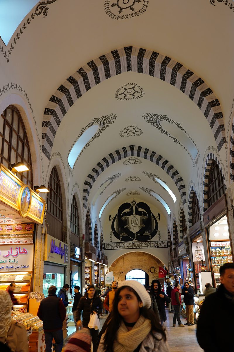 The long vaulted hall of the Spice Bazaar with shops on both sides and shoppers in winter coats